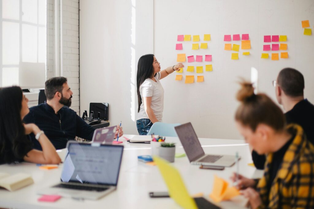 A professional team sitting around a work table planning a process, representing professional community, knowledge sharing, and growth around a digital product.