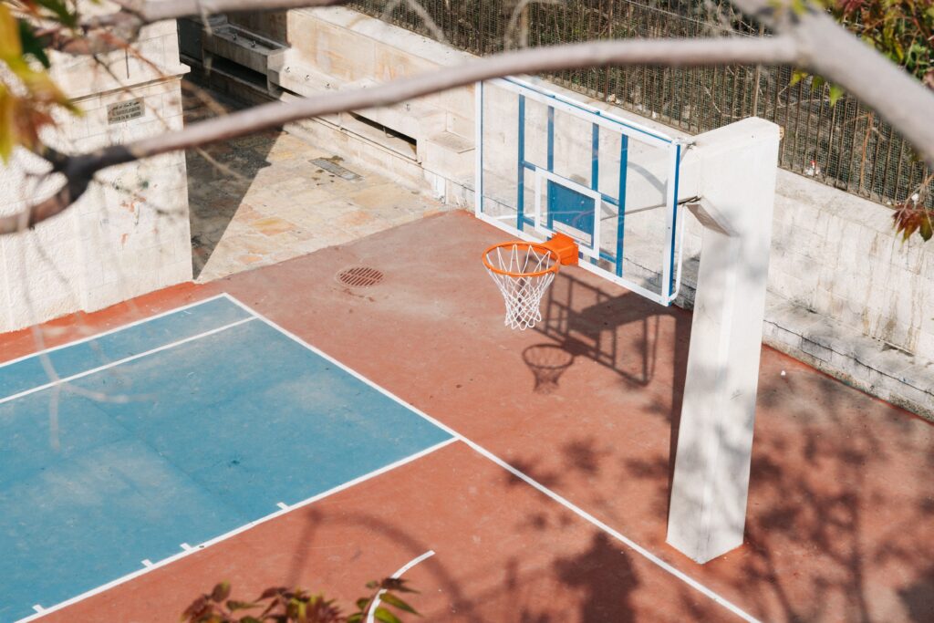 An empty basketball court with a hoop and shadows as a metaphor for the moment before momentum in sport and marketing