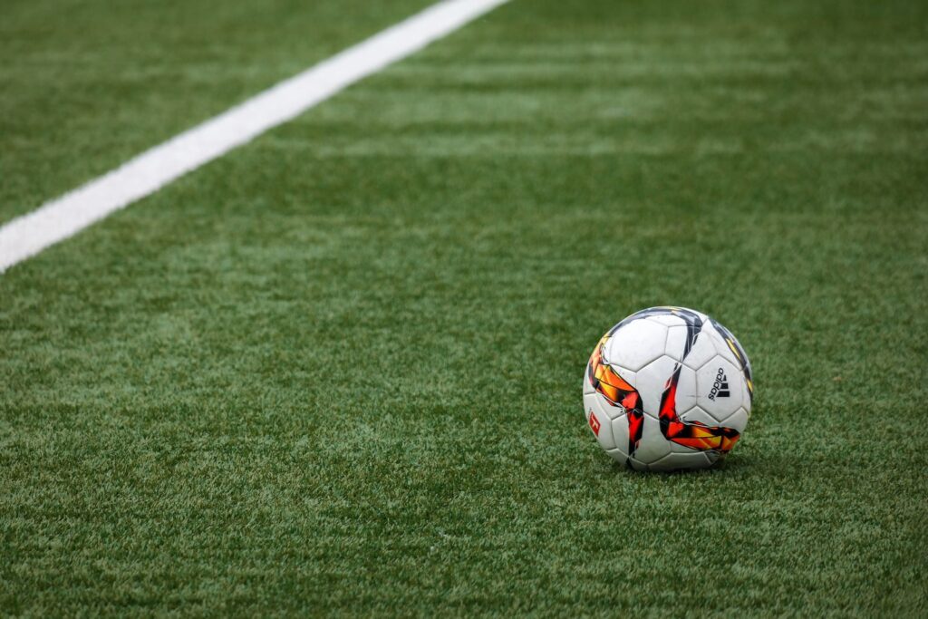A football on grass, representing a moment where a goal creates a happy side and a sad side, illustrating a reward system with winning and missing out.