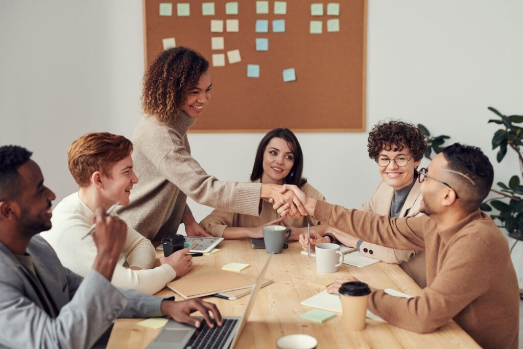 A group of people sitting around a table and collaborating, representing a community people return to through rituals, participation, and recurring value.