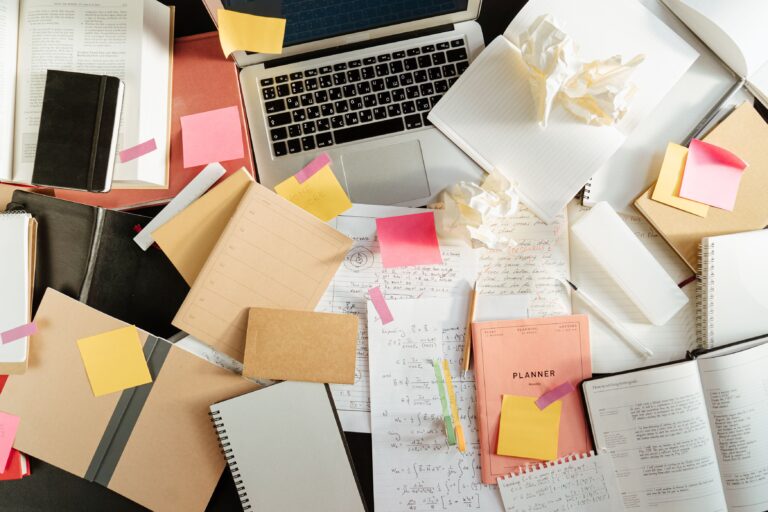 A work desk with sticky notes, a notebook, and a laptop as a metaphor for a process where the user invests thought and builds a decision