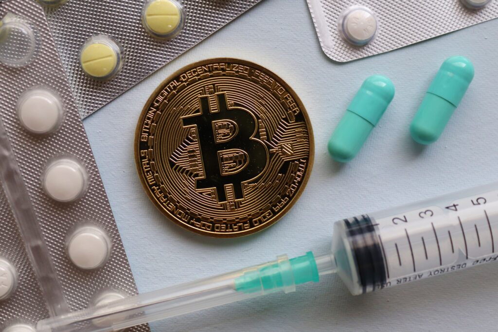 Close-up of bitcoin, pills, and a syringe on a table as a metaphor for forbidden markets, risk, and networks below the radar
